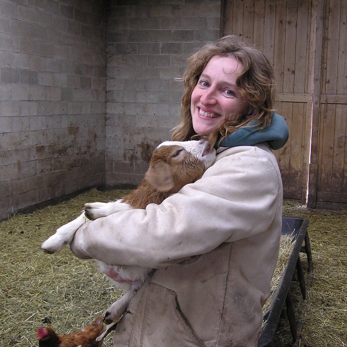 Norma holding a baby goat chewing on her hair