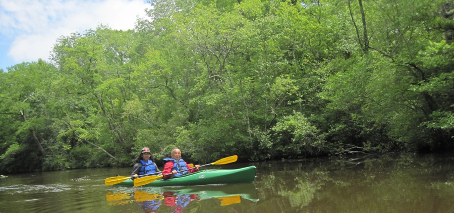 Dad and I in a green tandem kayak with the woods behind