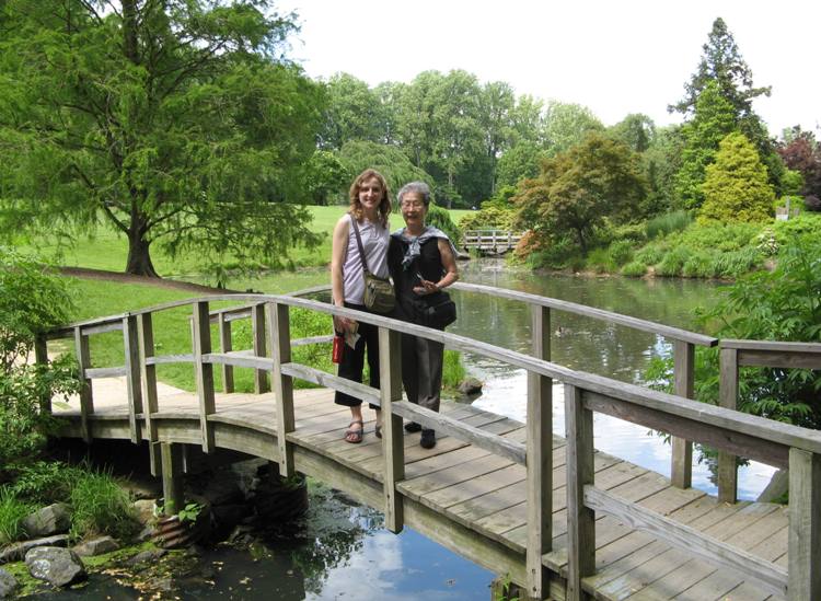 Norma and Mom standing on a foot bridge over a pond