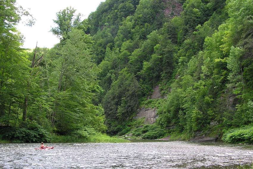 Kayaker paddling through riffles in canyon