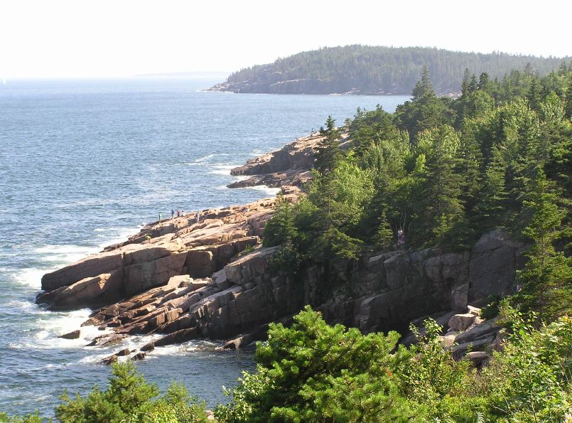 Rocky decline to the water with trees on the high ground