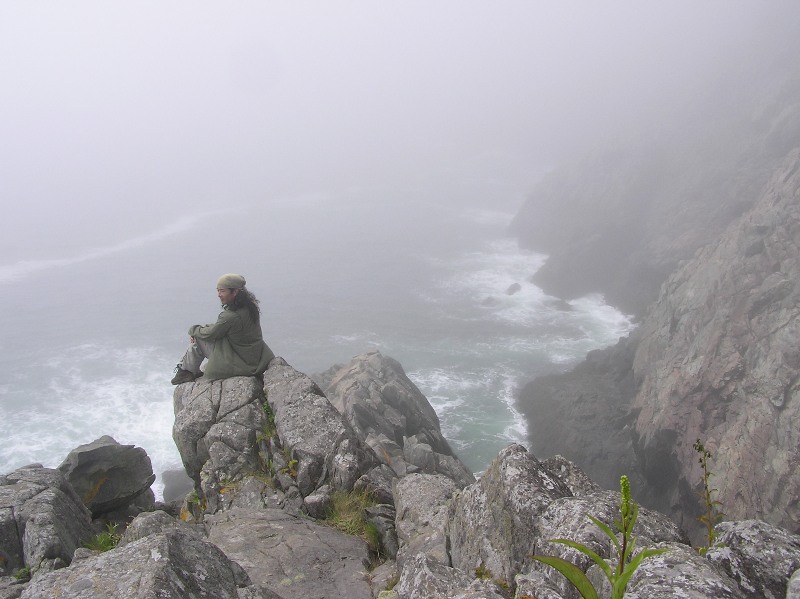 Me sitting on a high rock overlooking the ocean on a foggy day