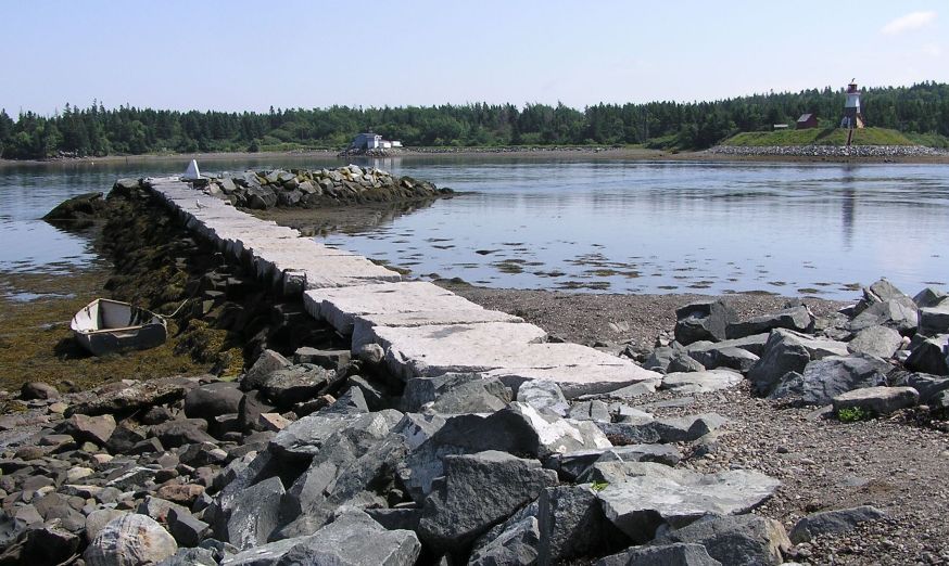 Big stone waterbreak, dinghy, and lighthouse