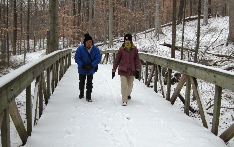 Dad and Norma crossing snow-covered wooden bridge