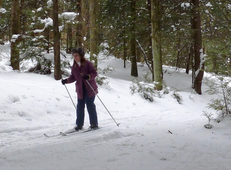 Norma skiing downhill through the woods