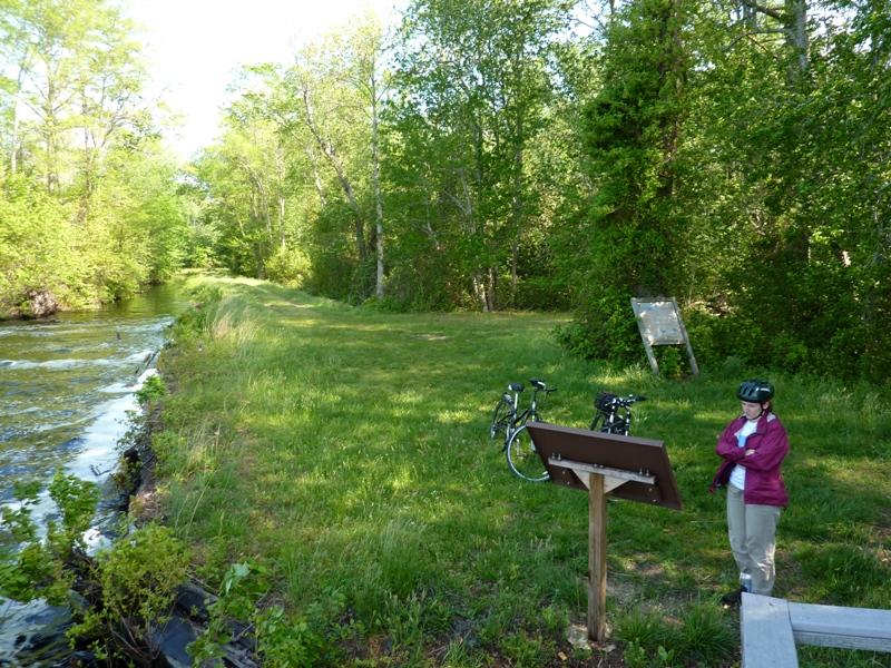 Norma reading sign near bicycles and waterway