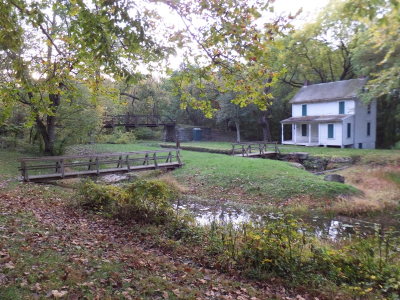 Grassy area, canal, three bridges, and old house