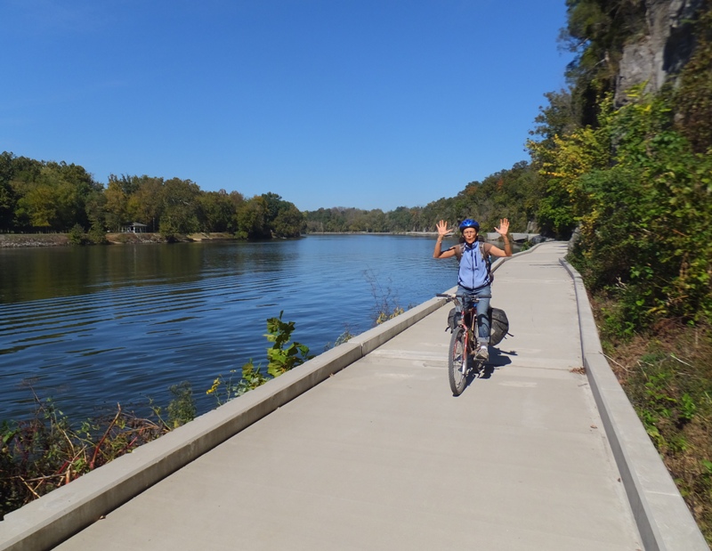 Carmen biking next to the Potomac with both hands in the air