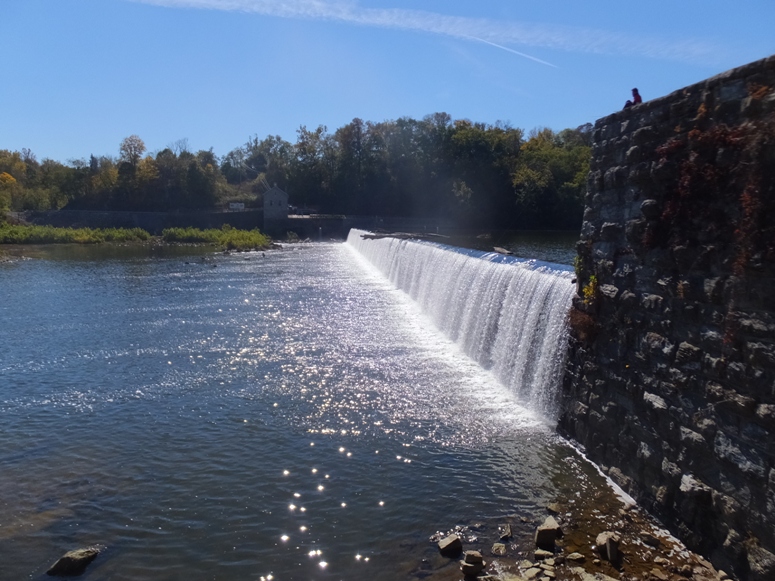 Water flowing over the dam with person sitting on top