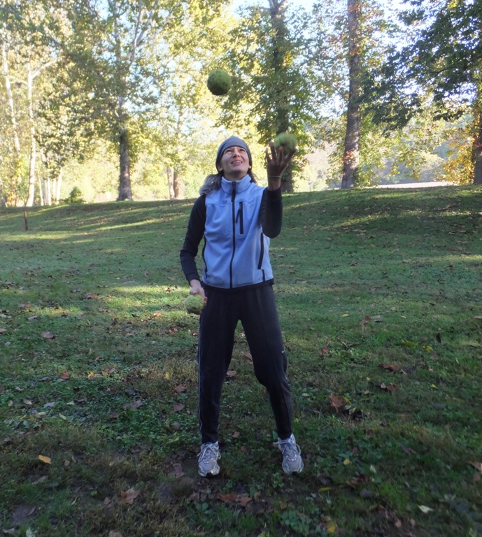 Carmen juggling three osage oranges