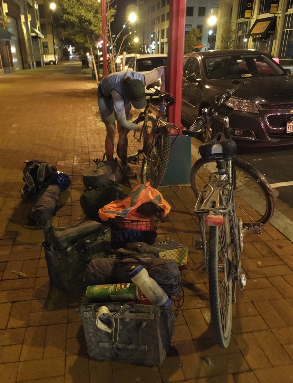 Carmen locking up her bike with our camping gear spread out on the ground