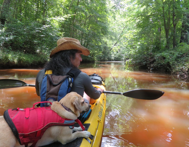 Daphne lying down on kayak with me in front