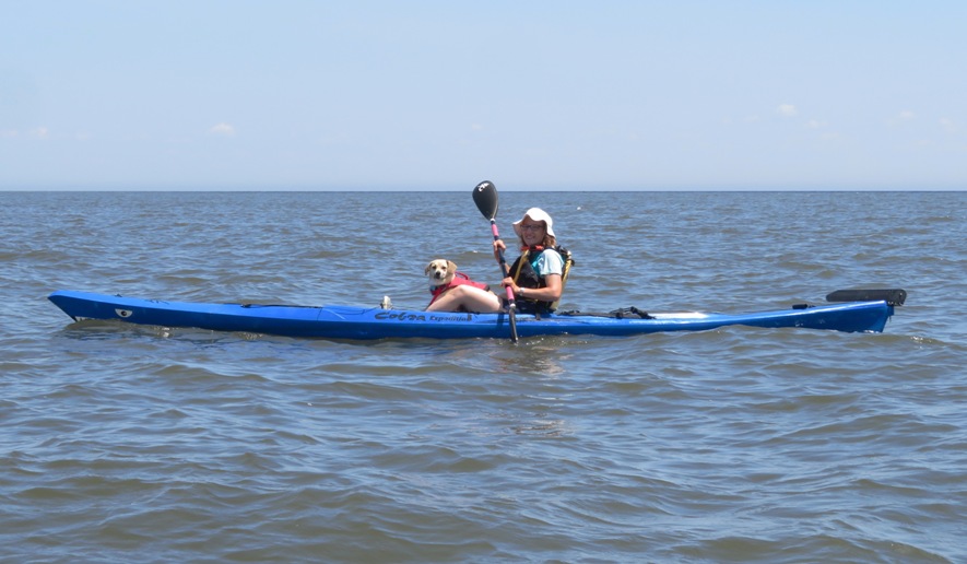 Side view of Norma kayaking with Daphne on board