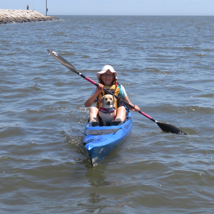 Front view of Norma kayaking with Daphne on board