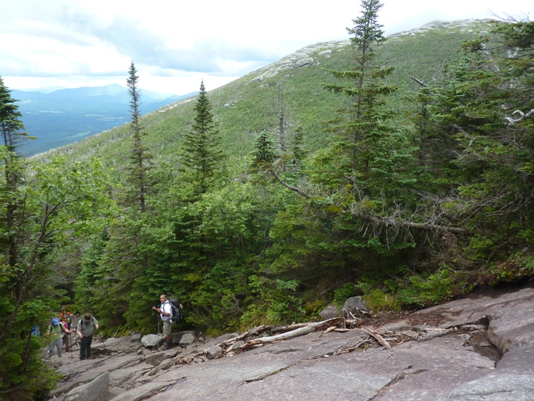 Several hikers make their way up a rock face incline