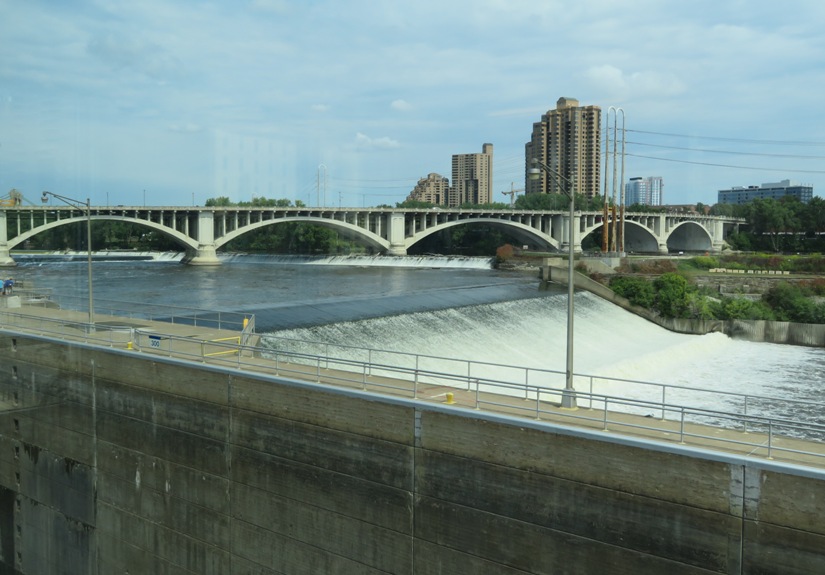 Water flowing over the dam with the city skyline behind