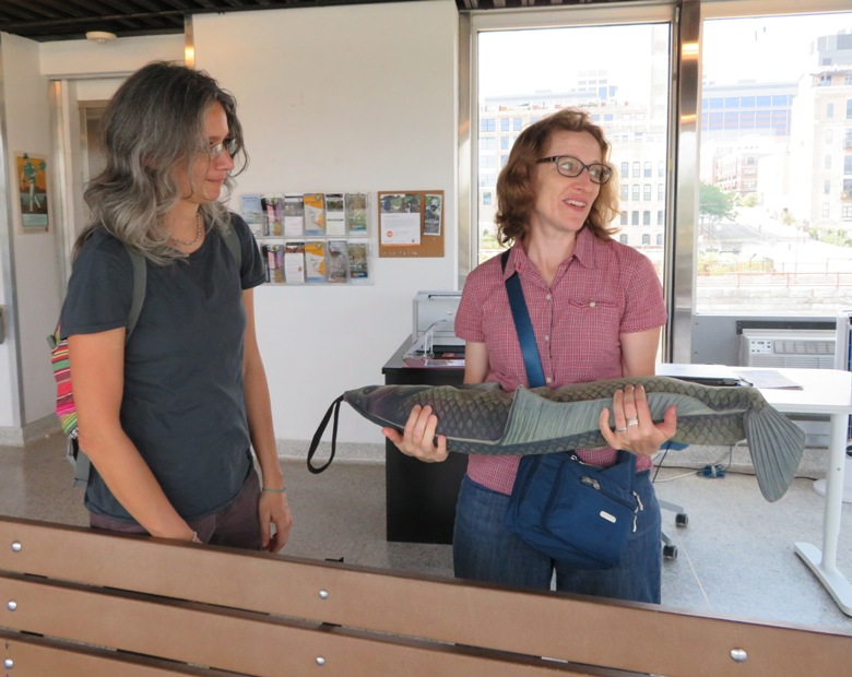 Norma holding a weighted model of a carp with Carmen watching