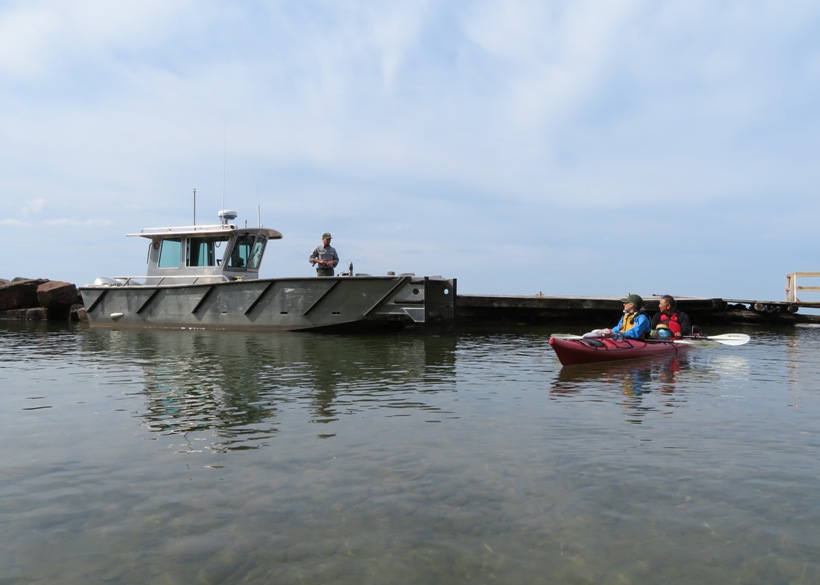 Steve and Carmen in their kayak talking to a ranger on a power boat