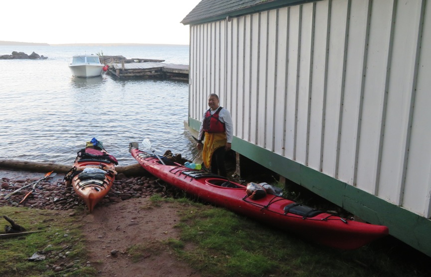 Steve standing by two kayaks next to boat house