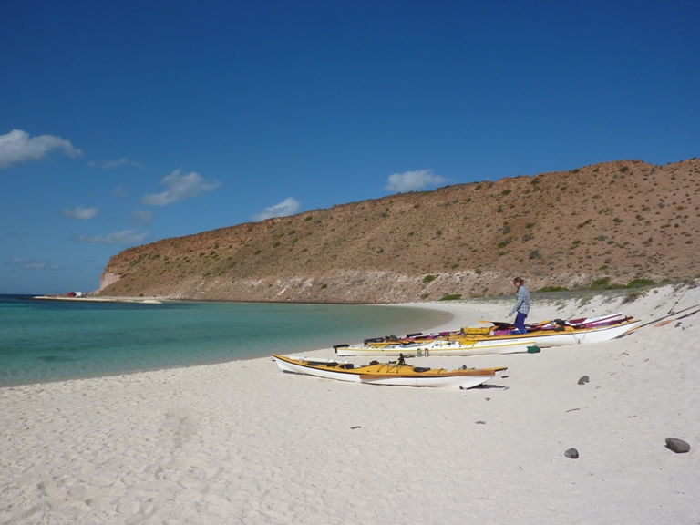 White sand of beach with kayaks and water