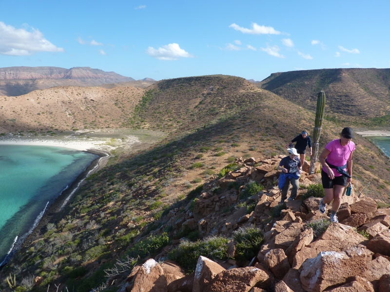 Family walking uphill on rocks with water view below