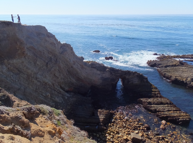 Couple on cliff with sea cave below