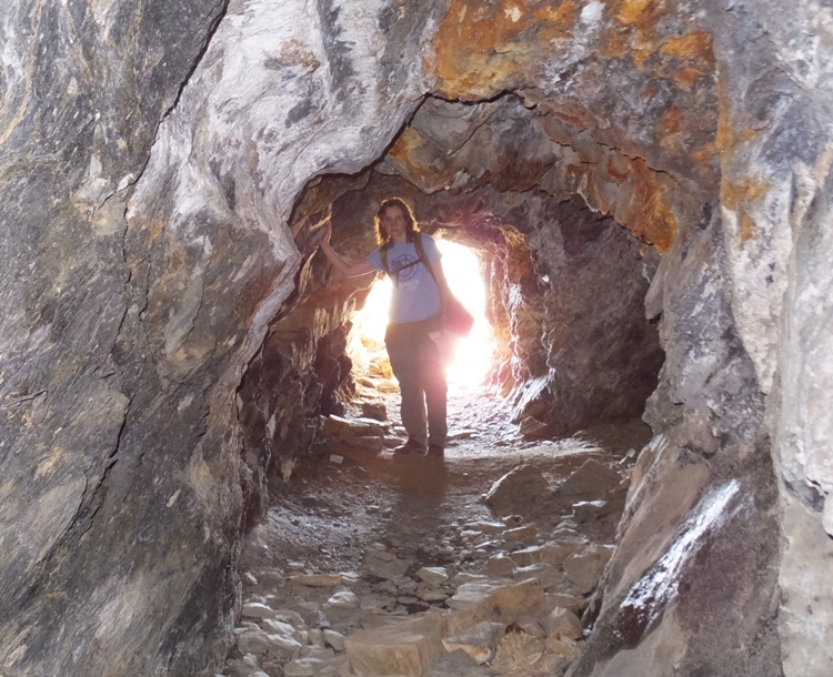 Norma standing near the illuminated entrance of a cave