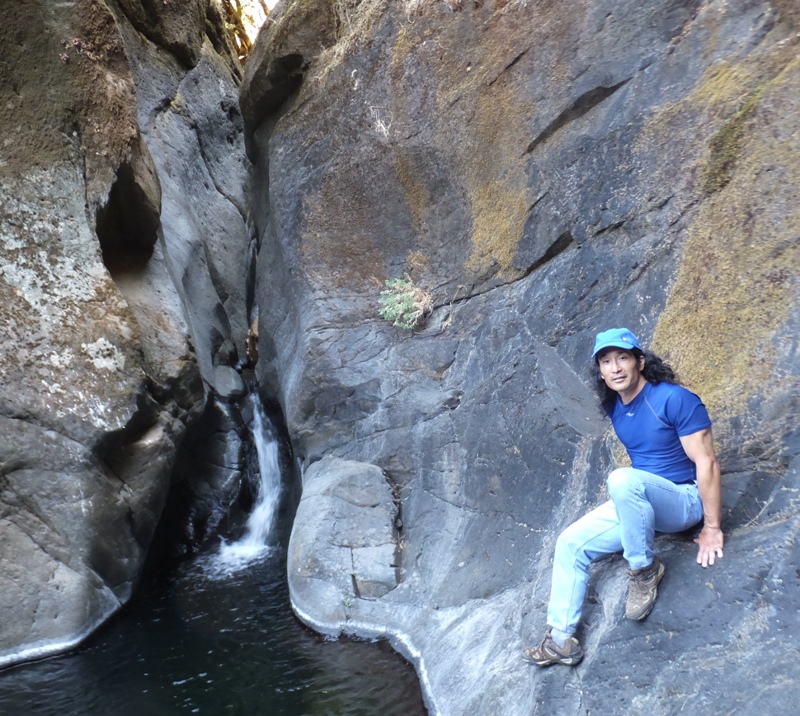 Me perched on rock with waterfall behind