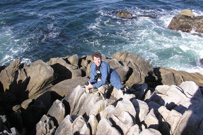 Ken on rocks with waves behind