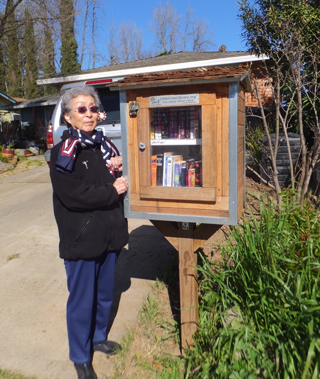 Mom next to Little Free Library kiosk