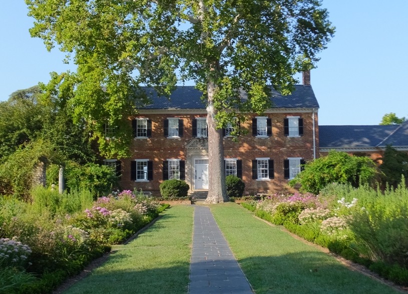 Main House, a brick mansion with a paver walkway and large tree