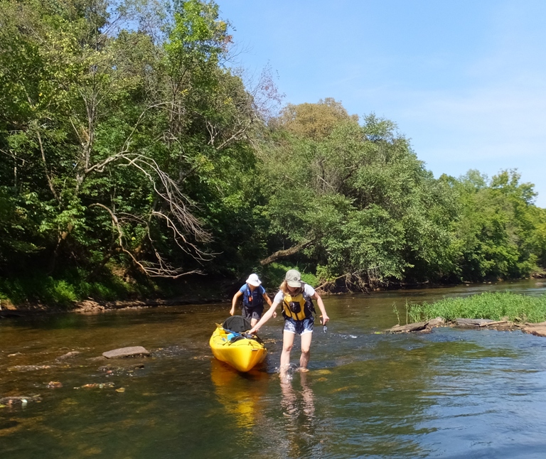 Norma and Janett portaging through shallow water