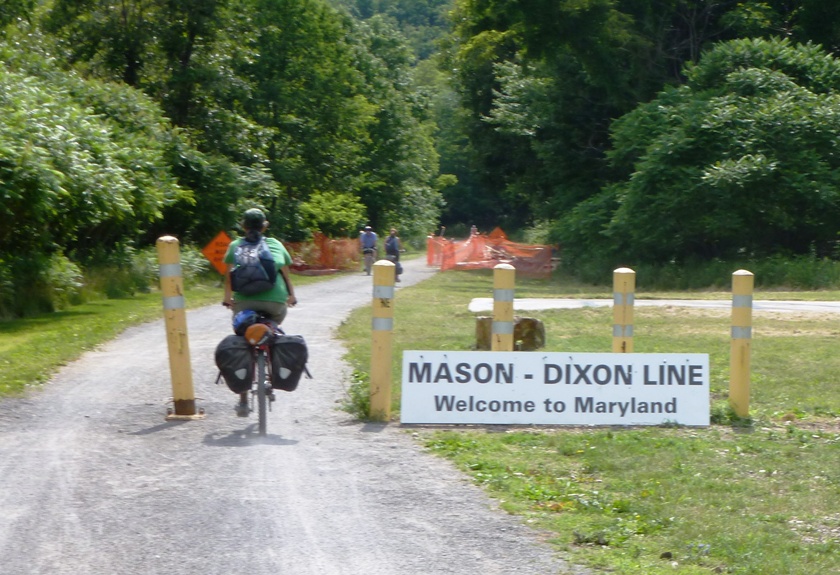 Carmen biking past Mason-Dixon Line sign