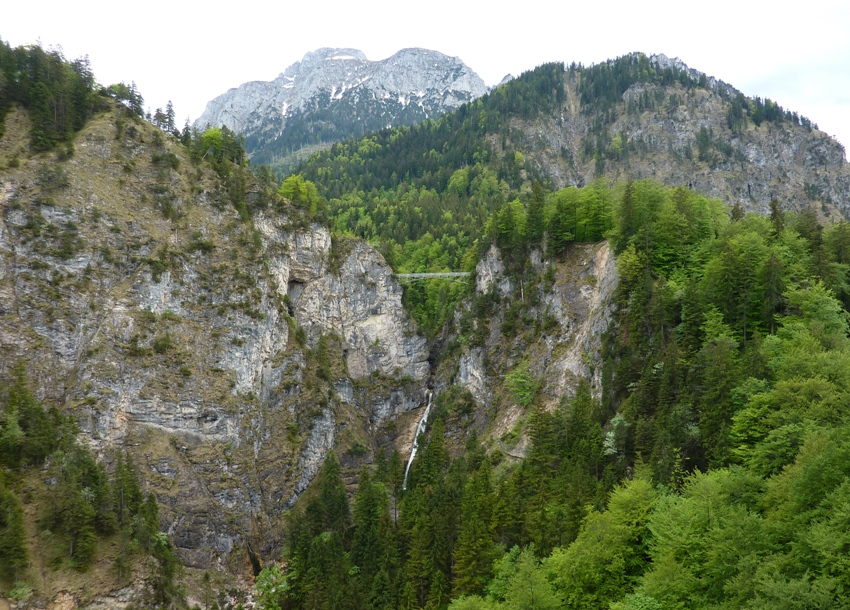 Bridge between rocky mountains with waterfall below