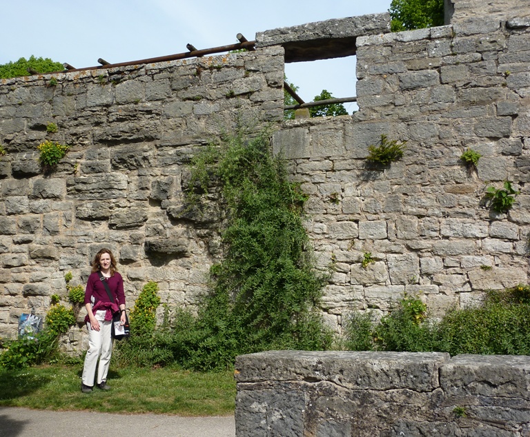 Norma standing by outer stone wall