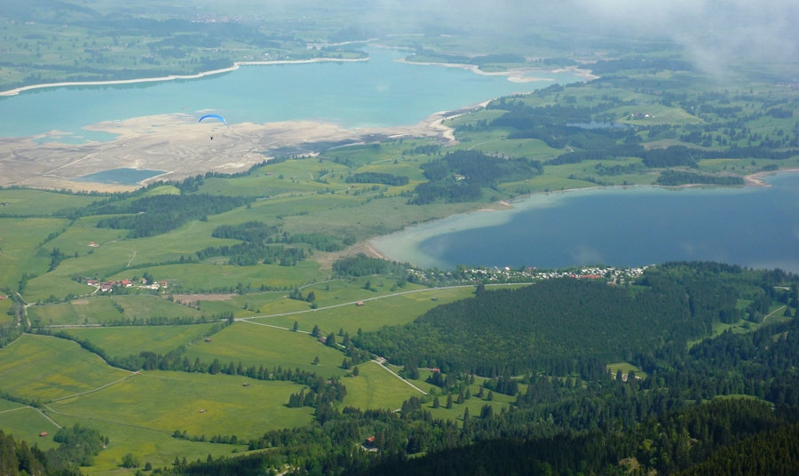 Water and greenery from high above along with blue parachute