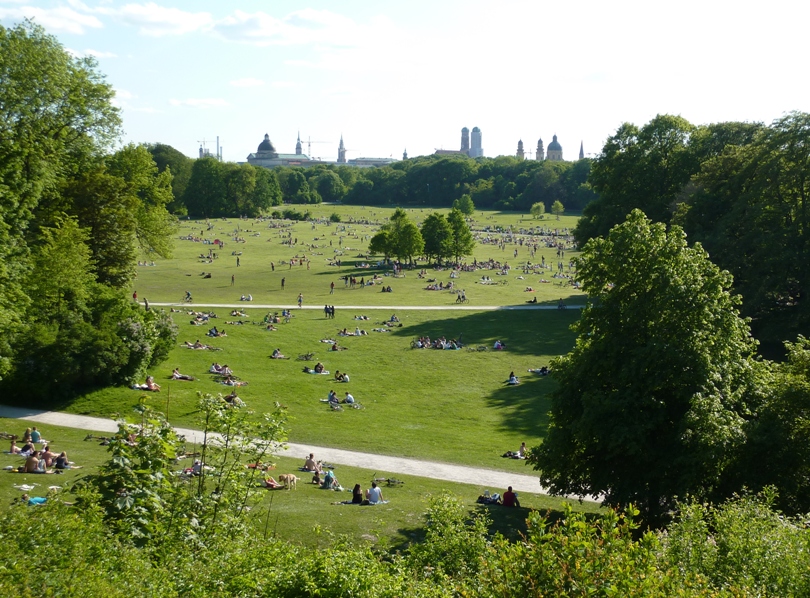 Lots of people in park with lots of grass and trees