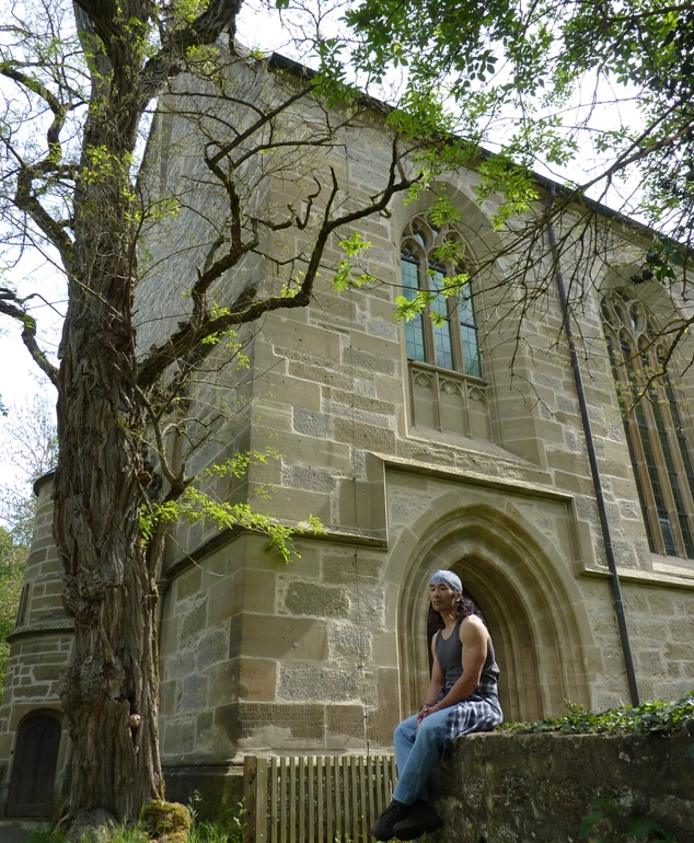 Me sitting on low stone wall with big stone building behind