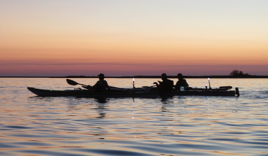 Three kayakers after sunset with their lights