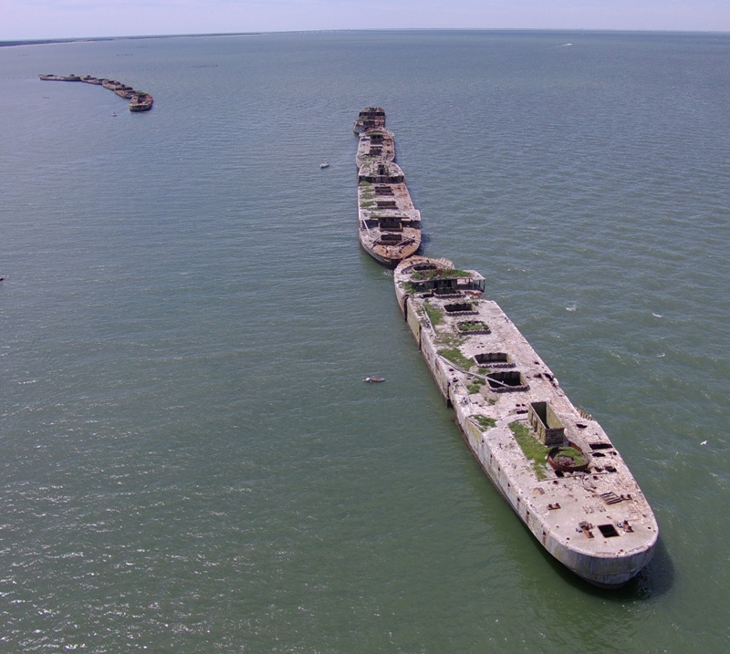 Tiny kayak next to big concrete ships