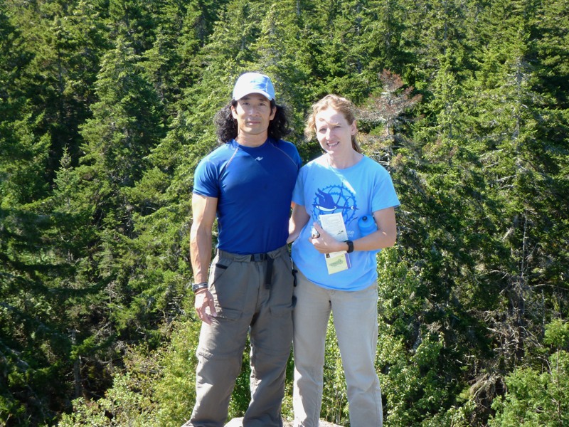 Norma and I standing at the summit with pine trees behind