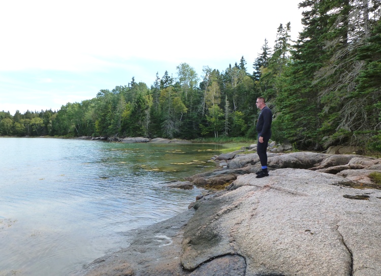 Vince standing on boulder by the water