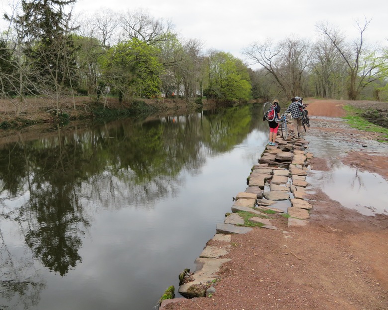 Bicyclists portaging over a wet area near the canal