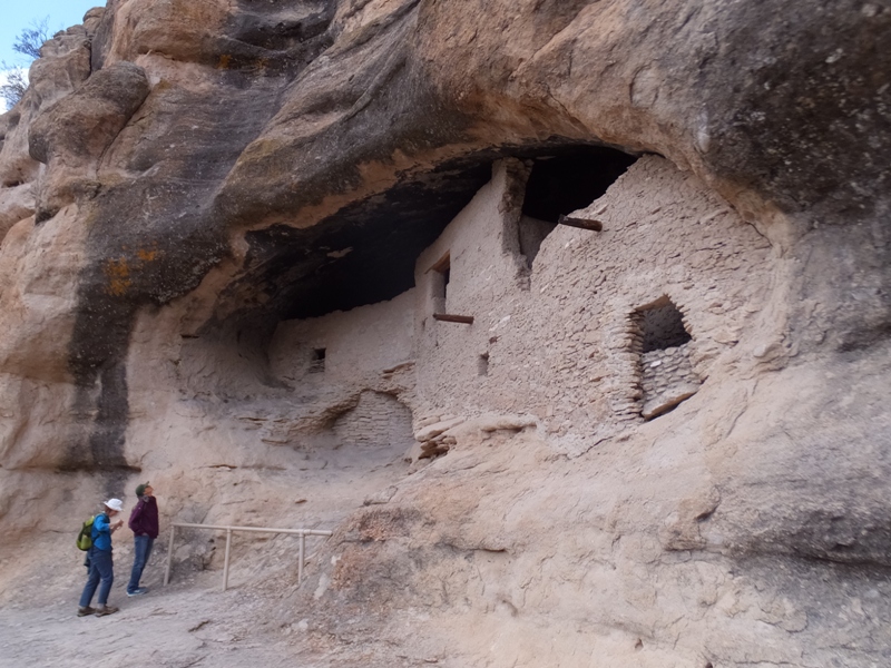 Norma reading about the cliff dwellings while Carmen looks at them