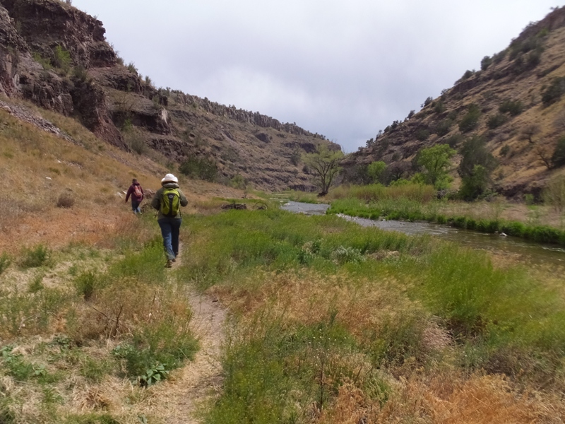 Carmen and Norma walking on a grass-lined trail near a stream