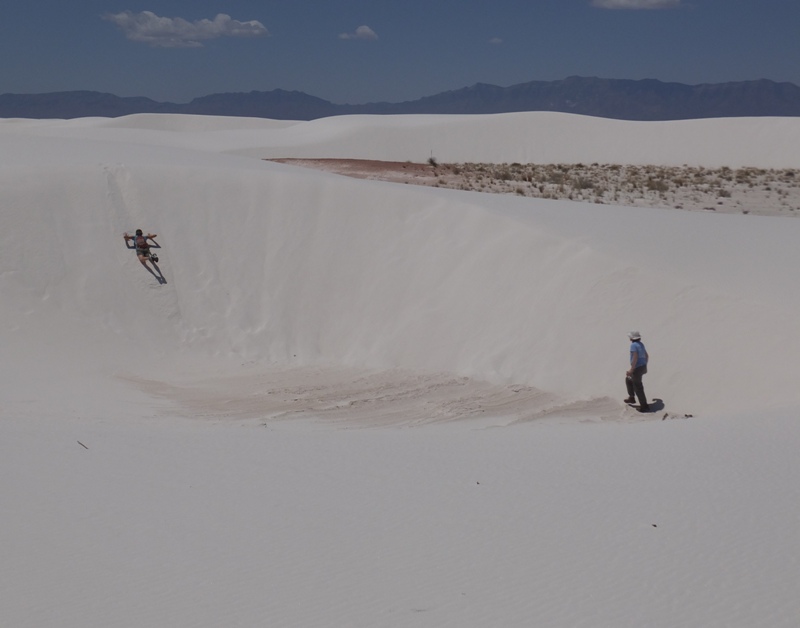 Carmen sliding down a dune on her belly