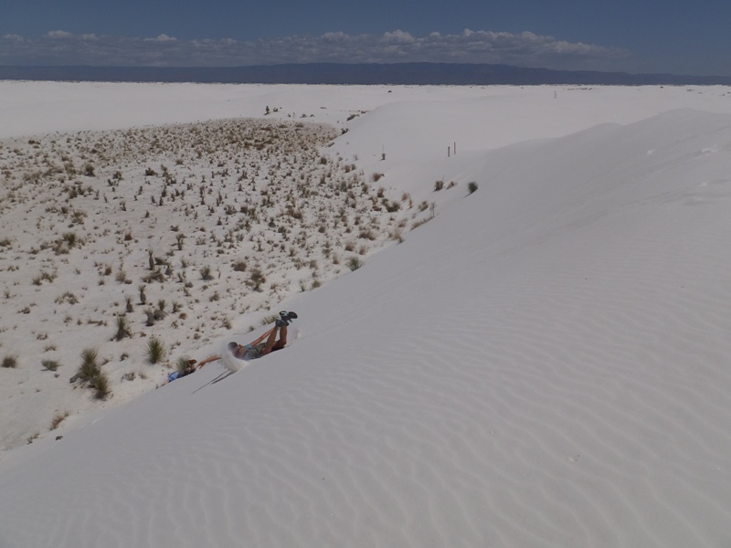 Carmen sliding down a dune on her belly, using her hands to grain speed