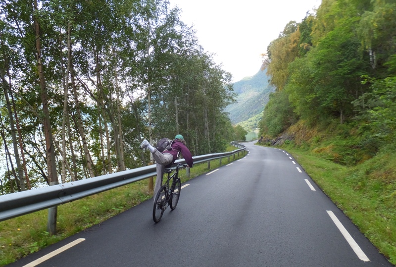 Carmen standing on moving bike with one leg in the air