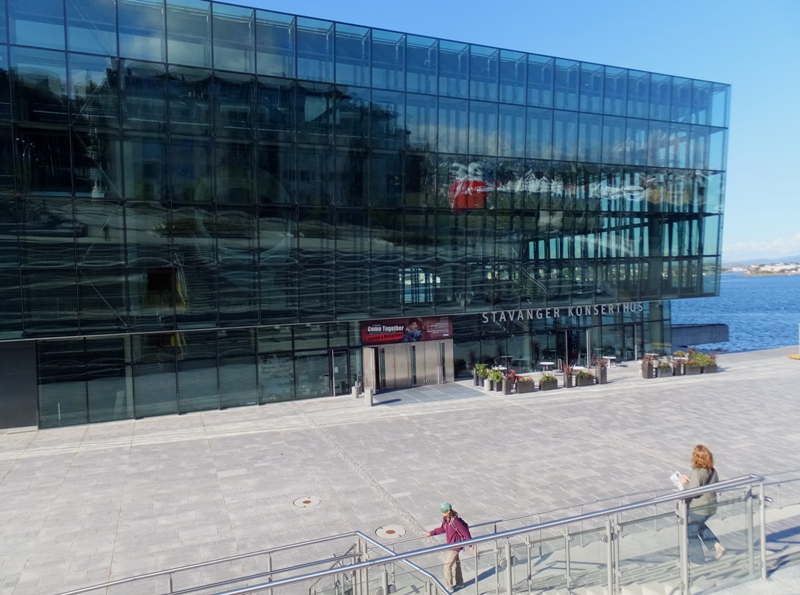 Norma walking to Stavanger Konserthus, a building with a lot of glass