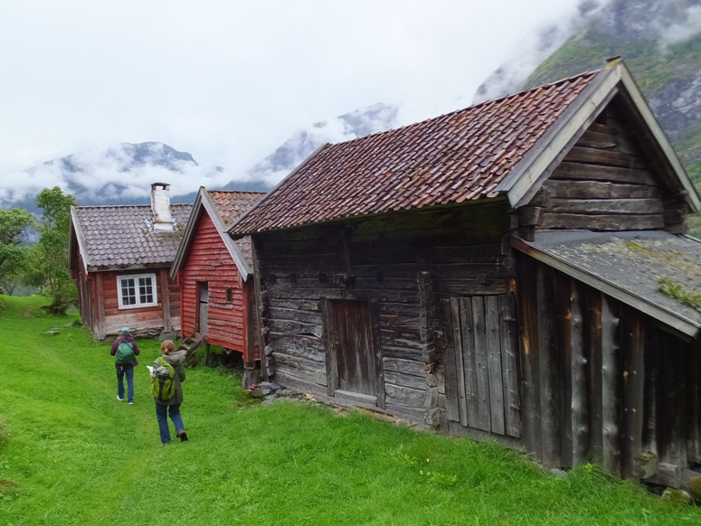 Norma and Carmen walking on very green grass past old homes